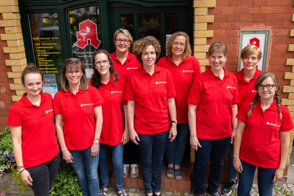 Das Bild zeigt ein Porträt des Apothekenteams der Plantagen Apotheke vor der Apotheke.