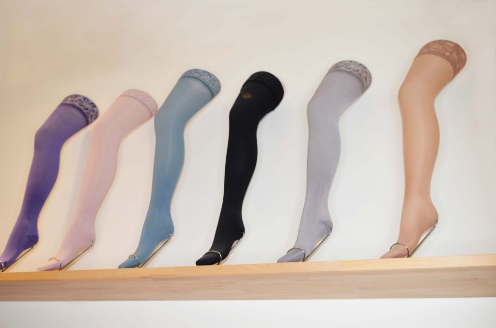 Das Bild zeigt mehrere verschiedenfarbige Musterkompressionsstrümpfe an Deko-Beinen.
